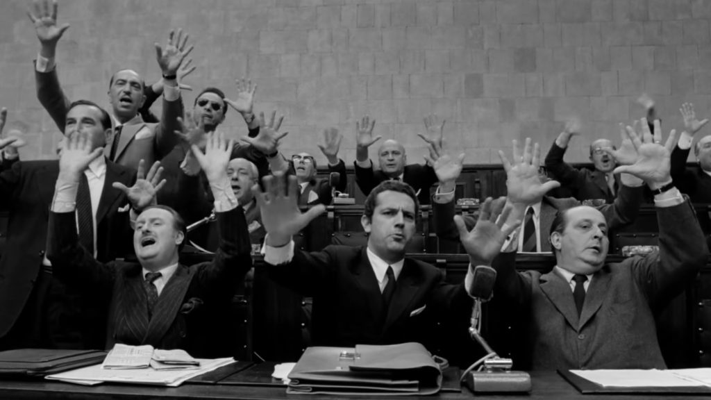 Una scena del film: tutto il consiglio comunale (tutti uomini) alzano le mani