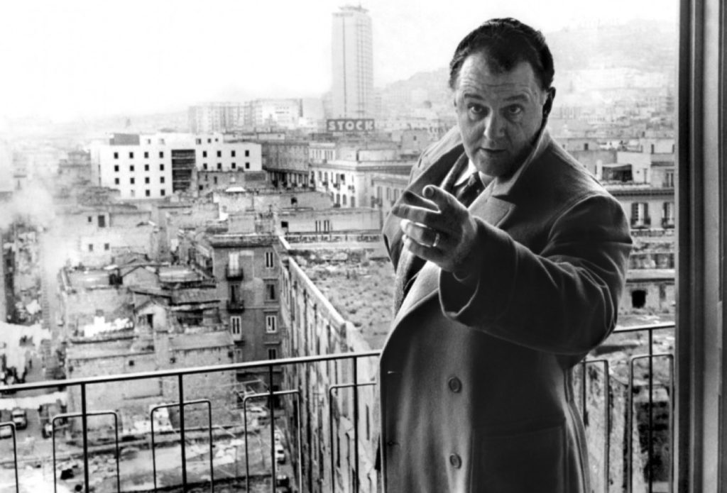 L'attore Rod Steiger in un fotogramma del film: si trova su un terrazzo da cui si vede la città dall'alto e in particolare il palazzo distrutto